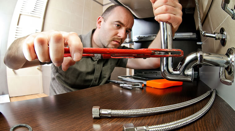Plumber installing flexible hoses under sink
